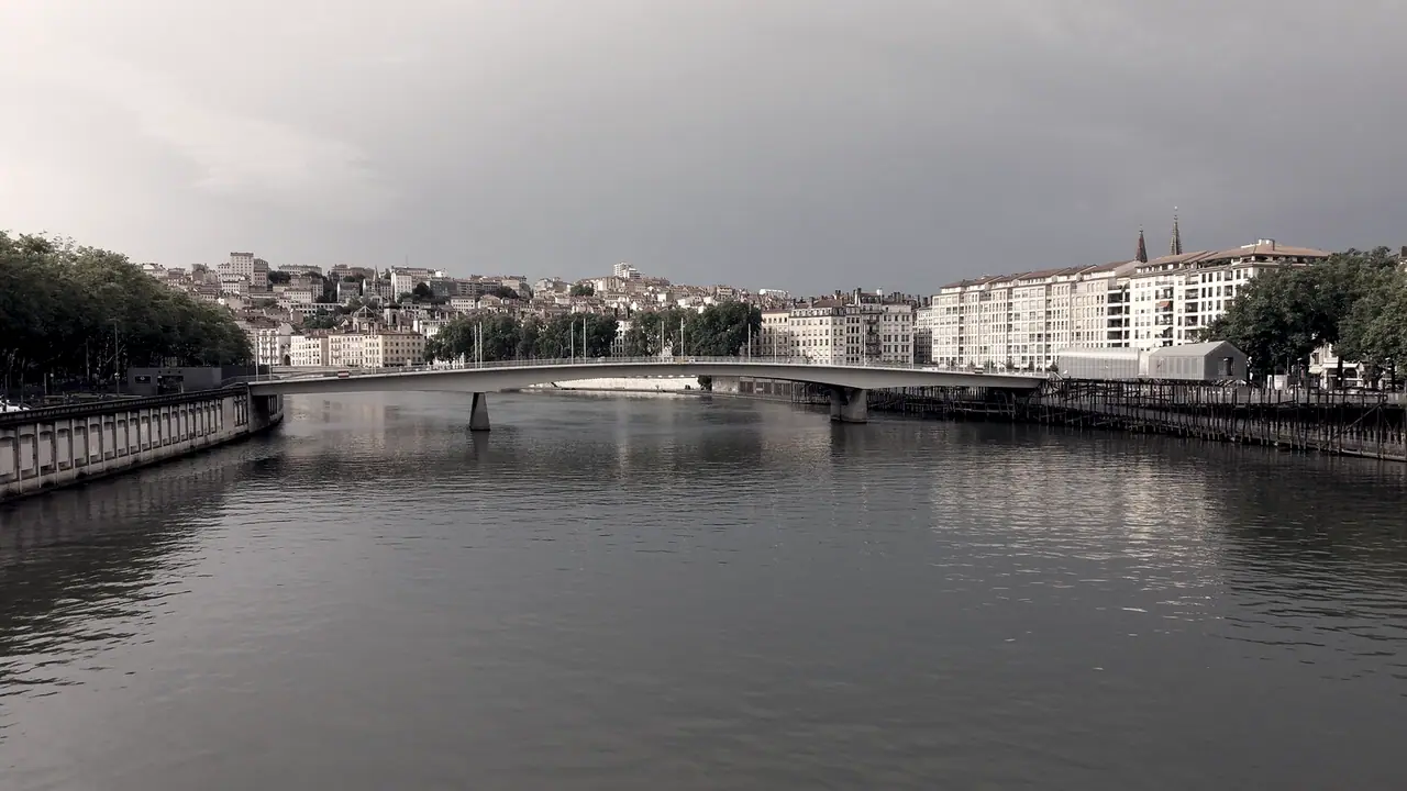 Pont franchissant une large rivière, avec les quais et les immeubles de la ville alignés sur les deux rives.