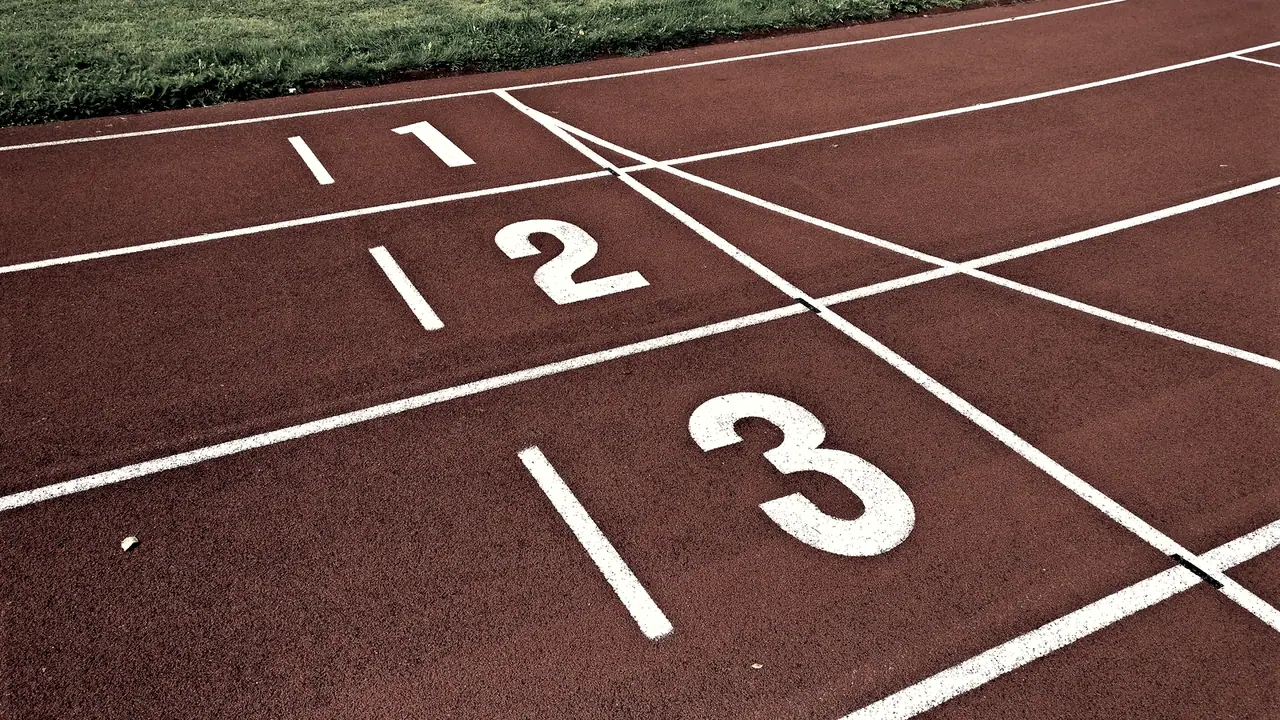 Lignes de départ d'une piste d'athlétisme, avec les couloirs numérotés 1, 2 et 3 peints en blanc sur le revêtement.