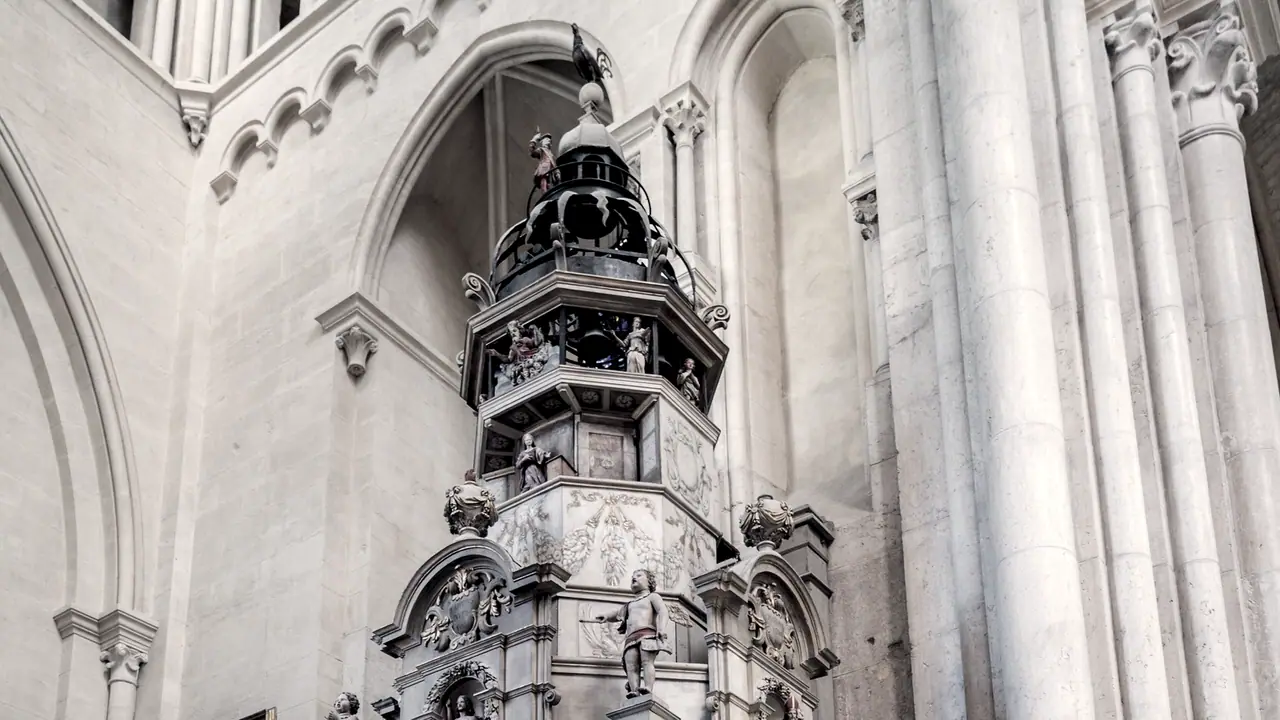 Couronnement d'une horloge astronomique dressée contre les piliers d'une cathédrale, avec ses automates, ses statuettes et son lanternon ajouré.