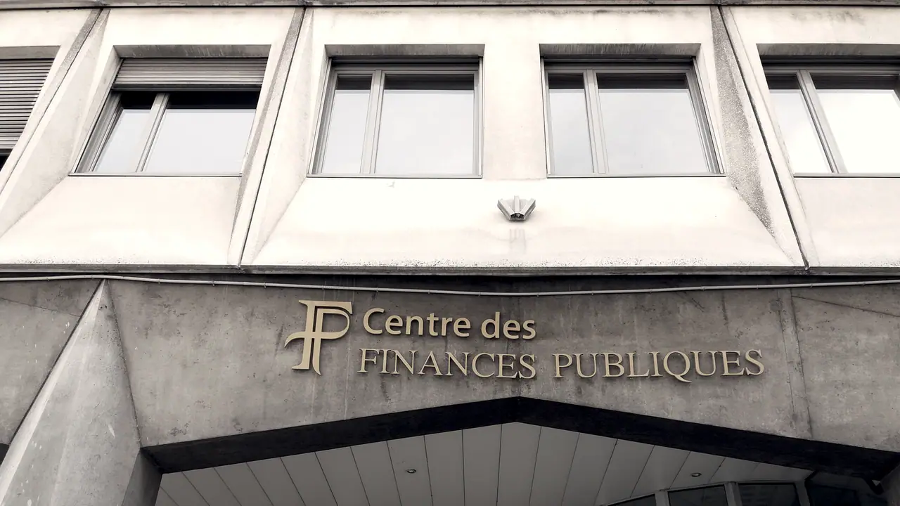 Enseigne en lettres de métal d'un centre des finances publiques fixée sur une façade de béton, sous une rangée de fenêtres.