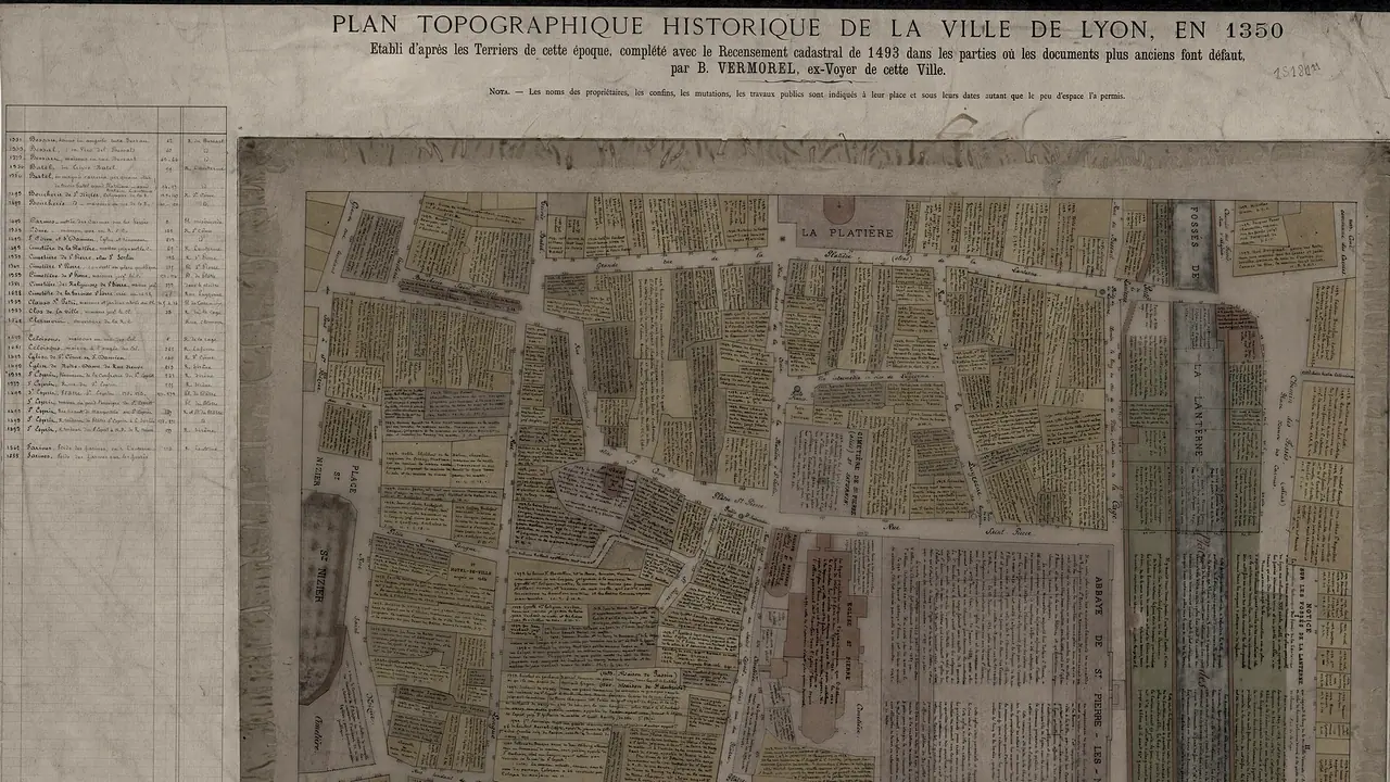Haut d'un plan ancien de Lyon, titré pour l'année 1350 : des îlots découpés en parcelles annotées à la main du nom de leurs propriétaires, le long de rues étroites.