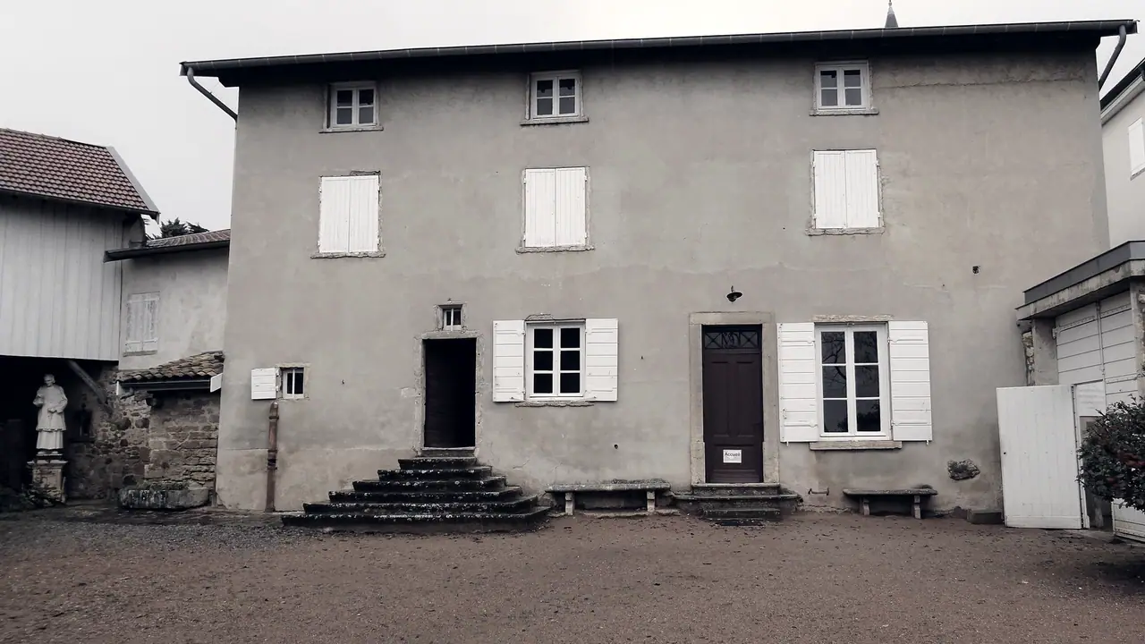 Maison ancienne de Dardilly à la façade crépie et aux volets blancs, précédée de deux perrons de pierre, sur une cour de terre battue.