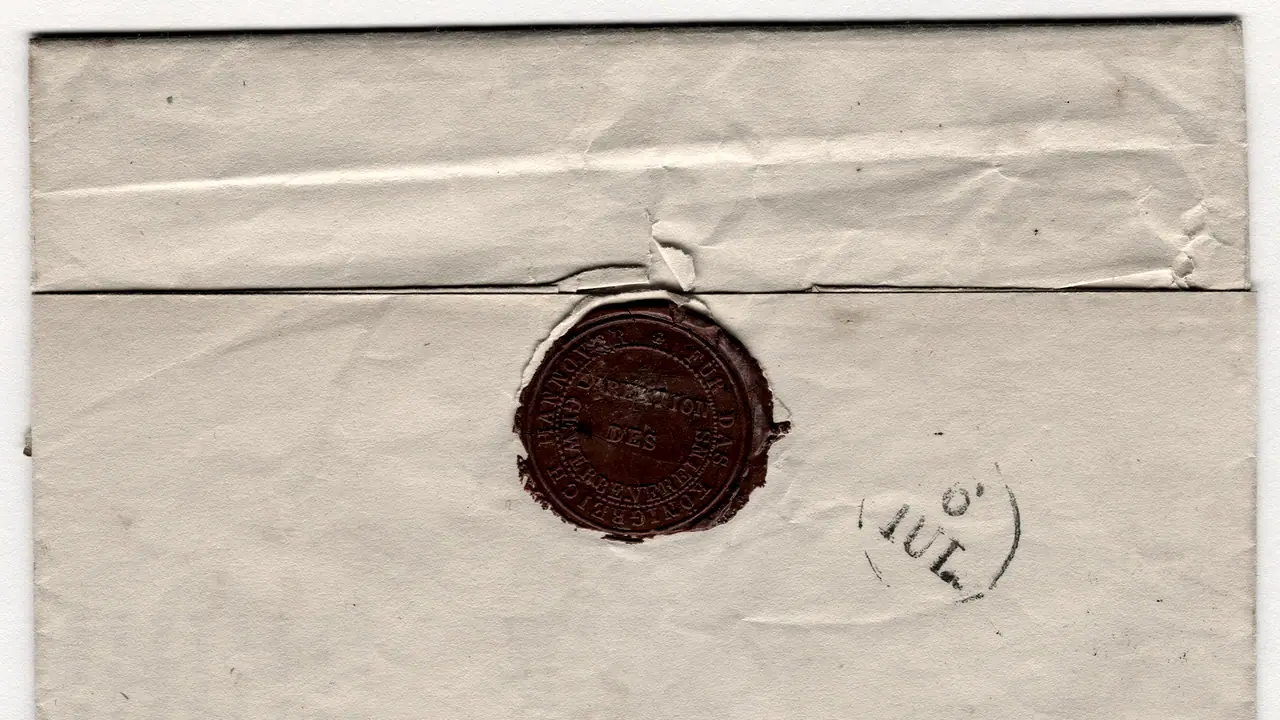 Cachet de cire sombre resté intact sur le rabat d'une lettre ancienne pliée, à côté d'un tampon postal rond daté du 6 juillet.