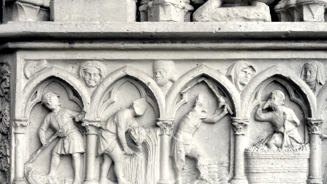 Bas-relief gothique sur le portail d'une église : sous quatre arcades, des paysans sculptés fauchent, moissonnent, battent le grain et foulent le raisin, chacun à son mois.