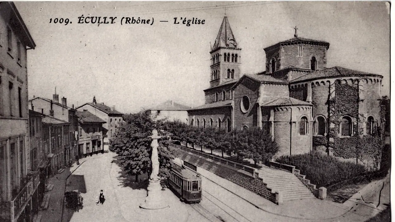 Carte postale ancienne d'Écully : l'église et son clocher au-dessus d'un talus planté, un tramway au pied des escaliers, sur une place bordée de maisons.