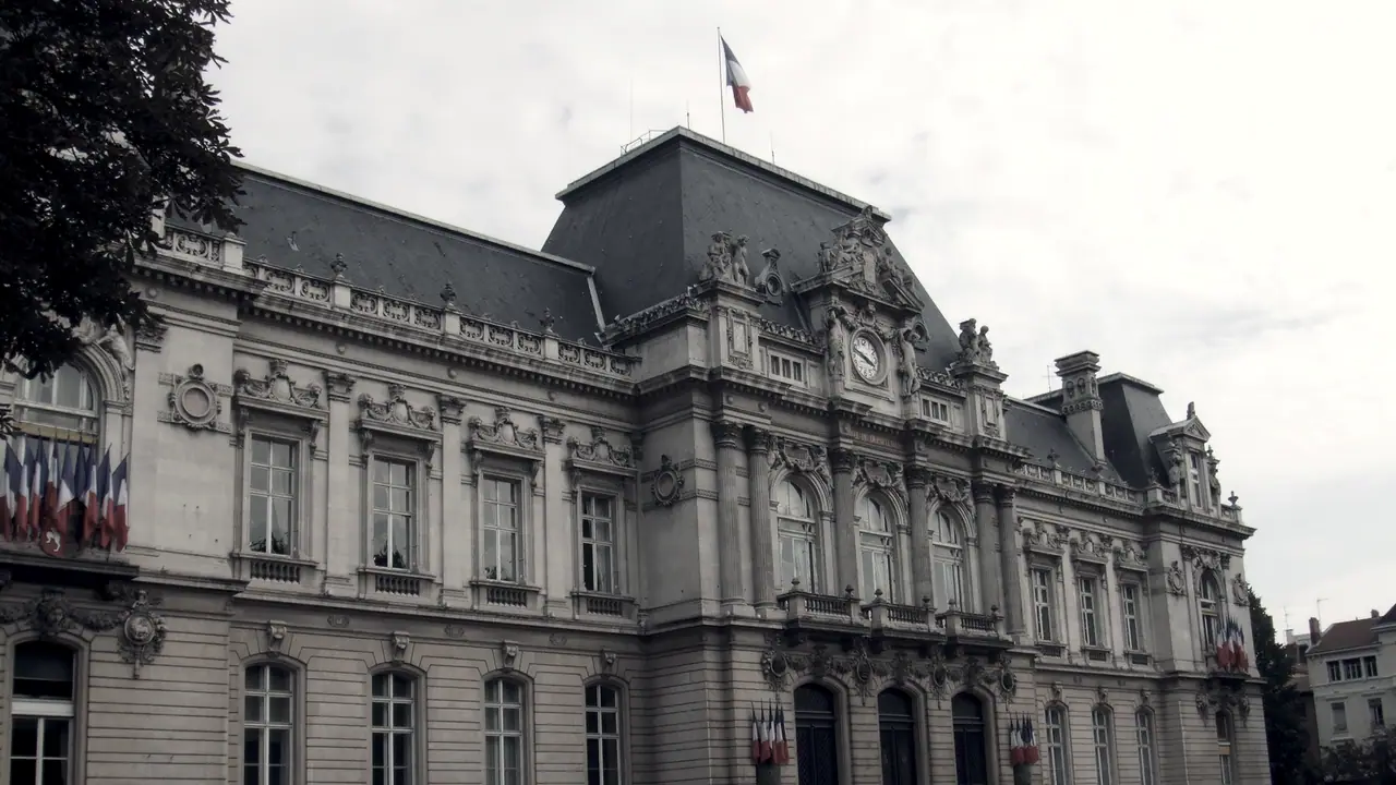 Façade d'un bâtiment public en pierre de taille, avec ses hautes fenêtres régulières et des lucarnes dans le toit d'ardoise.