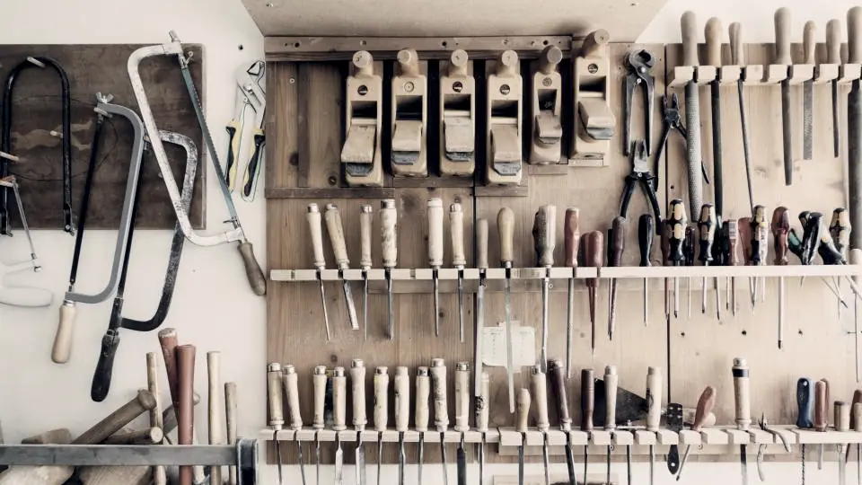 Panneau d'atelier couvert d'outils à main rangés et alignés, au-dessus d'un établi de bois.