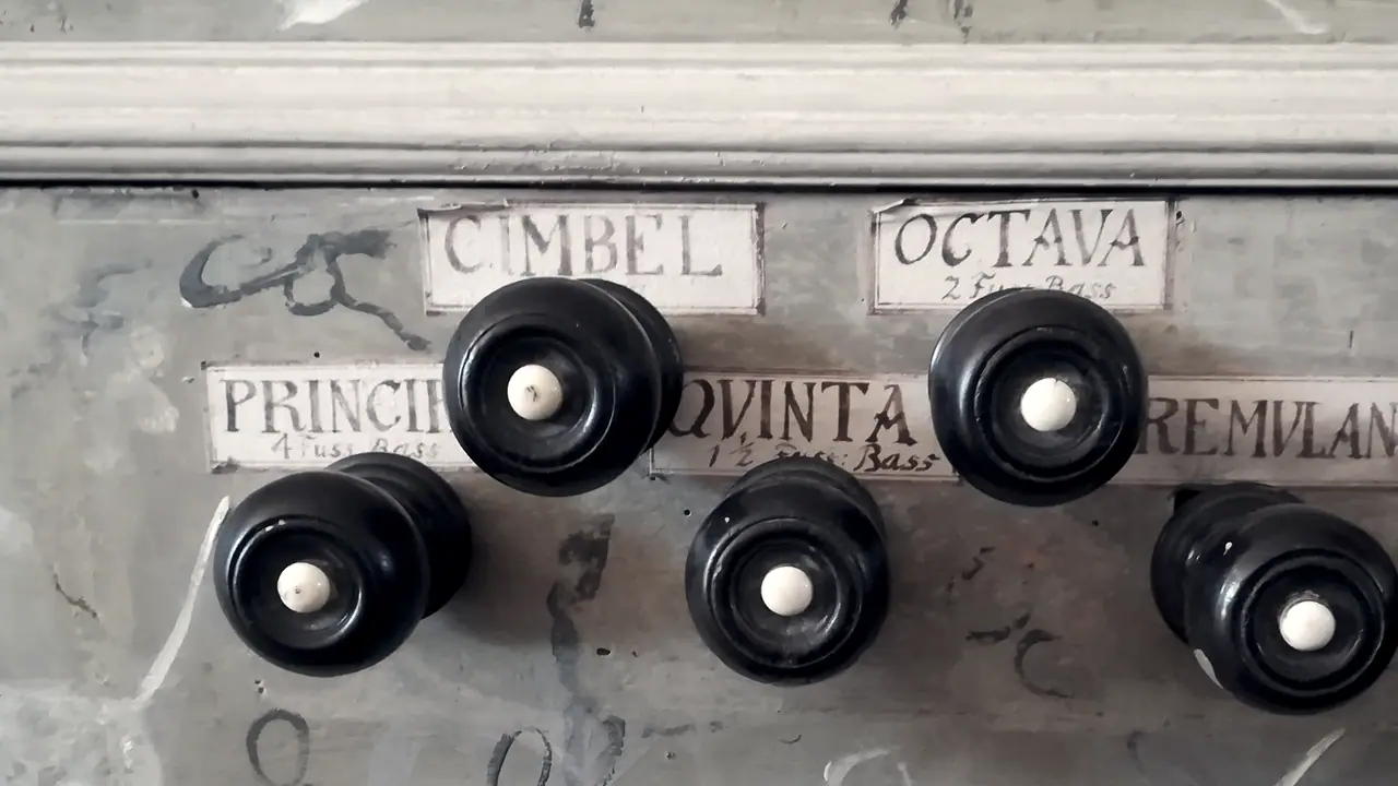Pommeaux de bois noir des tirants de registres d'un orgue ancien, devant leurs étiquettes peintes à la main : Cimbel, Octava, Quinta, Principal.