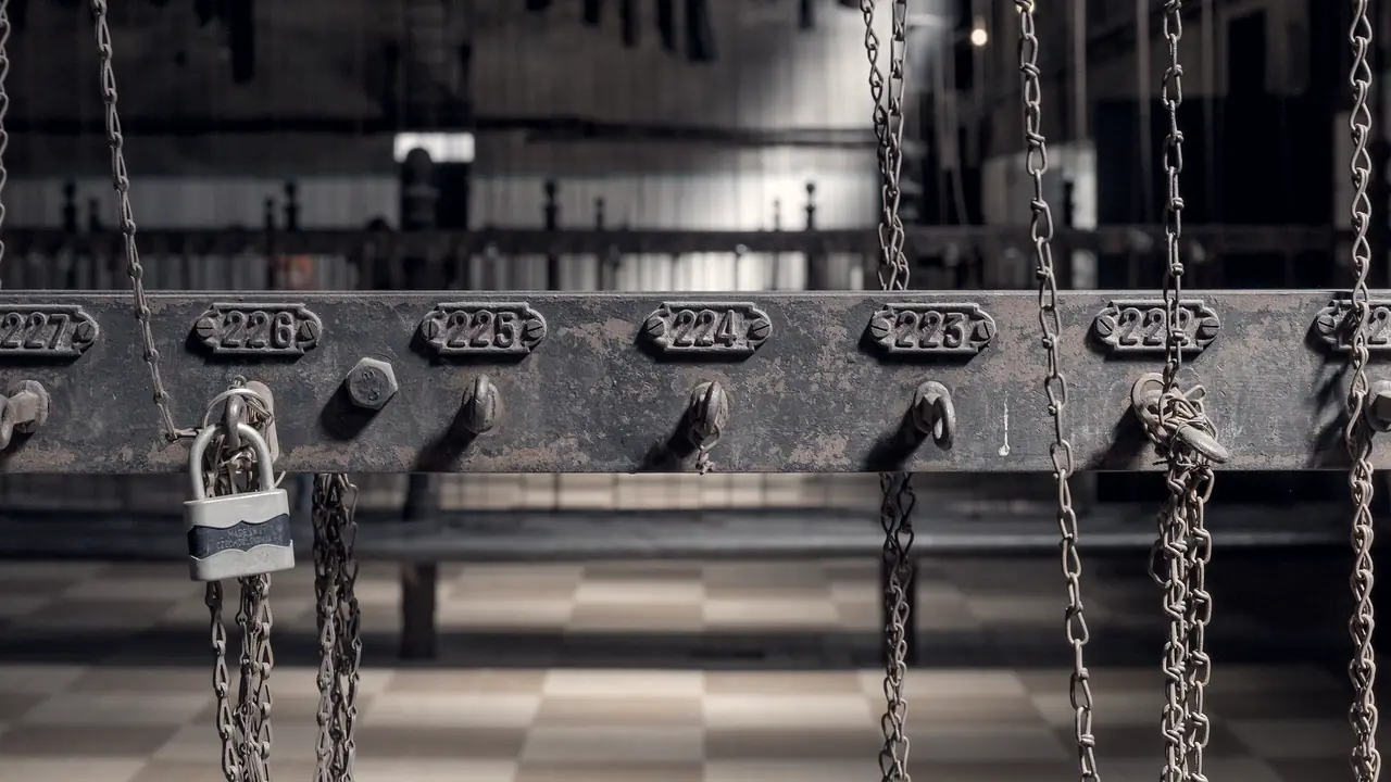 Barre de fer rouillée dans la salle des pendus du puits Couriot, à Saint-Étienne : sous chaque numéro, un crochet retient la chaîne qui hissait les habits d'un mineur.