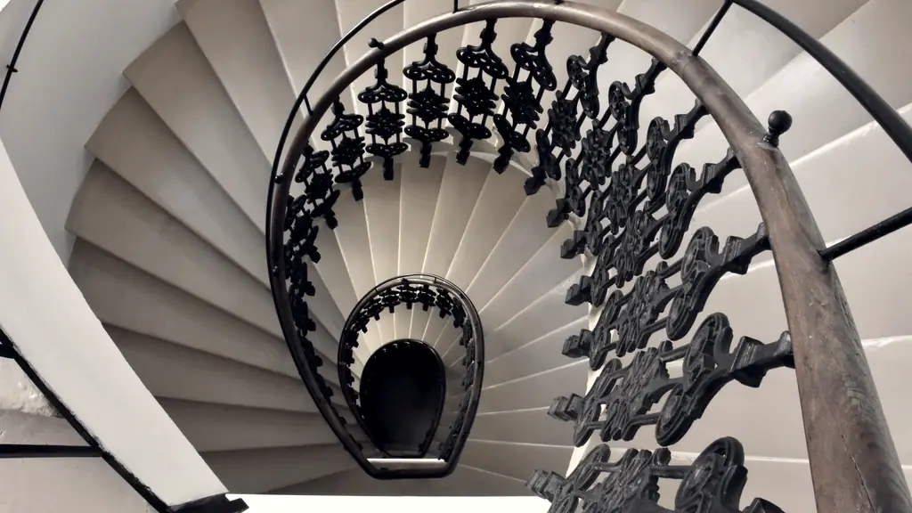 Escalier en colimaçon vu du dessus : les marches et la rampe de fer forgé s’enroulent en spirale vers le bas.