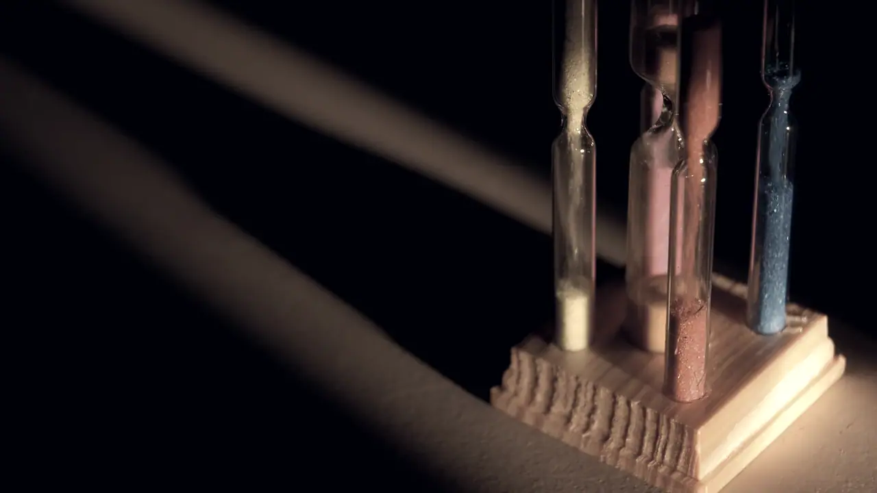 Trois petits sabliers alignés sur un socle de bois, le sable figé dans chacune des ampoules de verre.