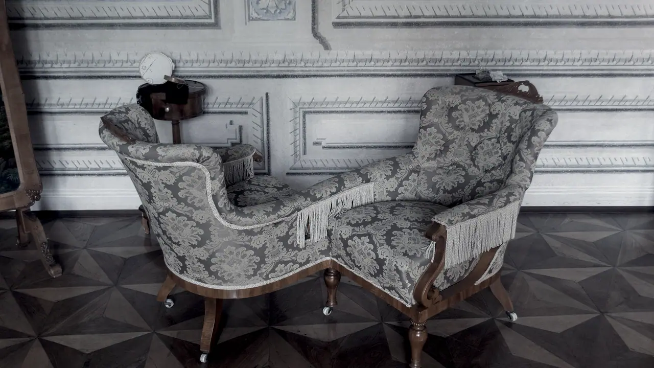 Fauteuil ancien en S à deux places jointes, chaque siège tourné dans la direction opposée à l'autre, sur un parquet en étoile devant un mur à moulures.