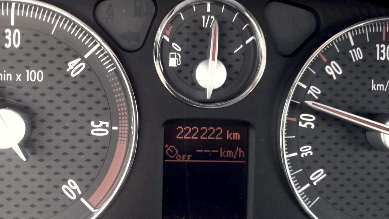 Tableau de bord d'une voiture : entre le compte-tours et le compteur de vitesse, la jauge de carburant à moitié et l'afficheur qui indique 222 222 km.