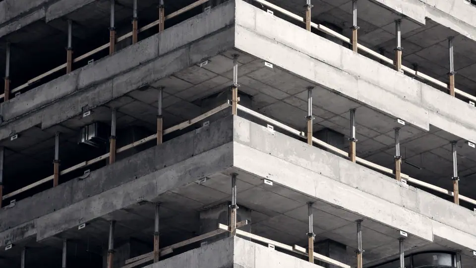 Immeuble en construction : les planchers de béton se superposent sans façade, les étages du bas déjà fermés et ceux du haut ouverts.