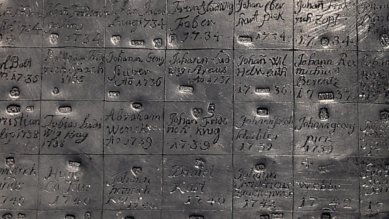 Cases d'une table d'étain où des orfèvres ont gravé leur nom et une année, de 1734 à 1742, chacun avec son poinçon frappé dans la même case.