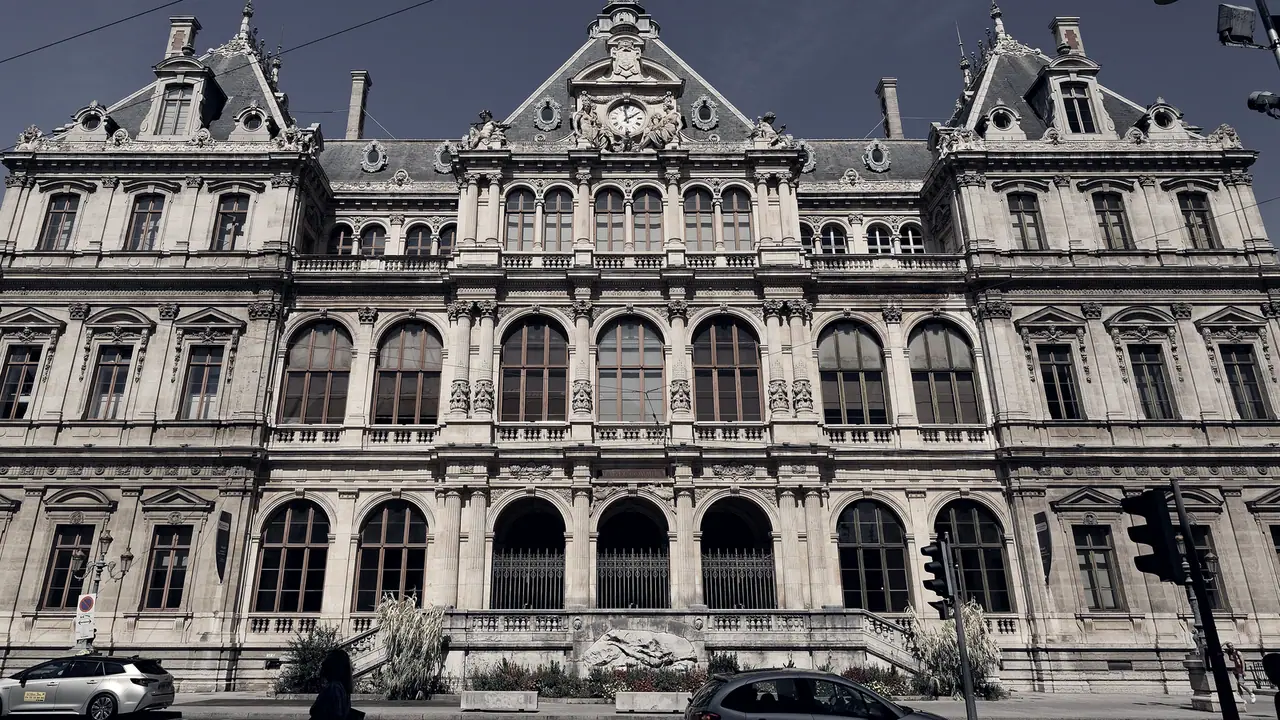 Façade monumentale d'un palais du commerce, avec trois niveaux d'arcades, une horloge au centre sous un fronton sculpté et des toits à lucarnes.