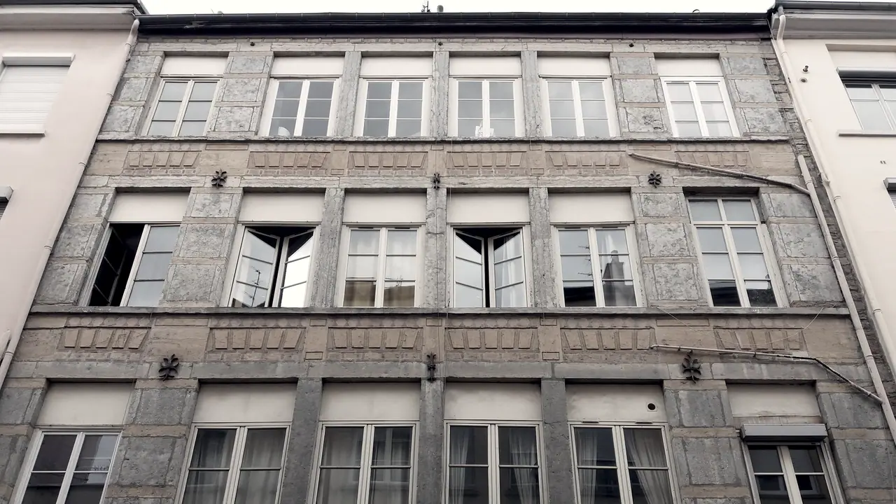 Haut d’une façade d’immeuble de la Croix-Rousse, avec ses rangées de hautes fenêtres à petits bois et ses bandeaux de pierre entre les étages.