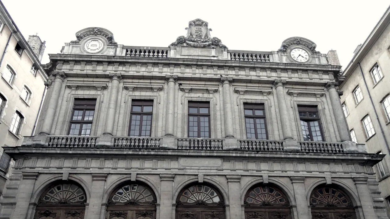 Façade de la loge du Change, dans le Vieux Lyon : colonnes engagées, hautes fenêtres à petits bois, balustrades, une horloge et un cartouche sculpté au sommet.