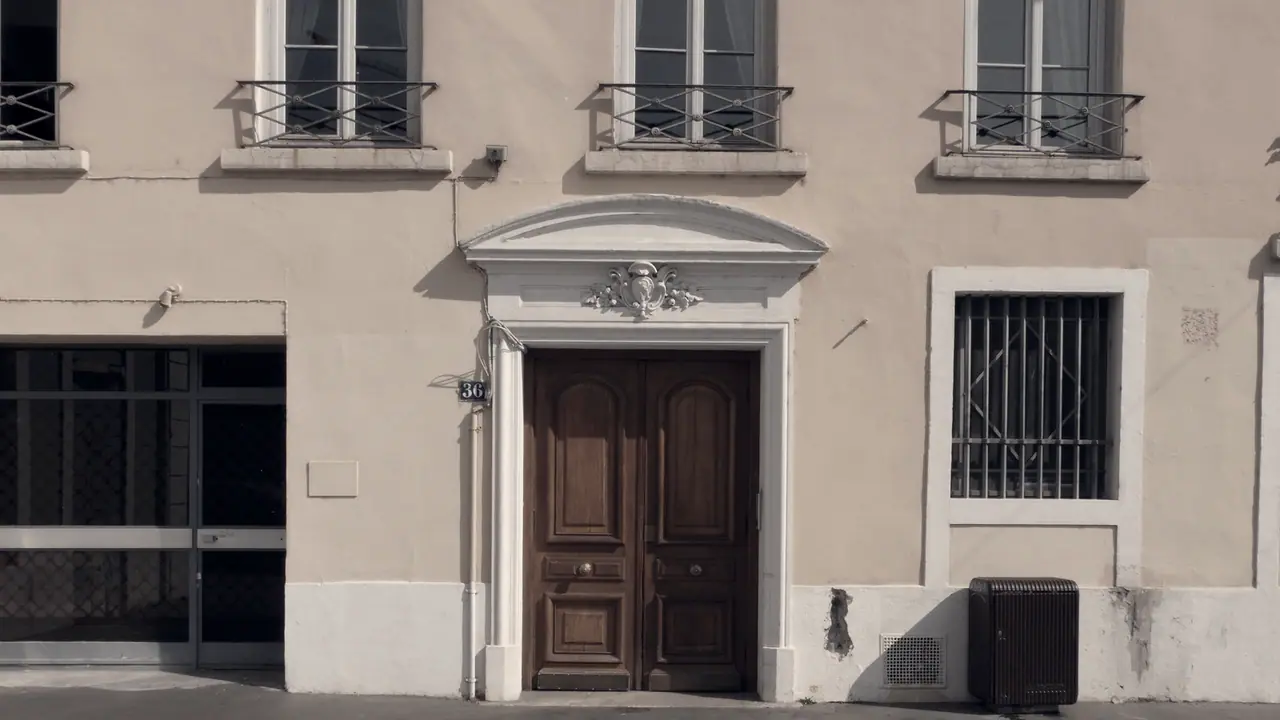 Porte d’immeuble à deux battants de bois moulurés, sous un fronton cintré orné d’un cartouche sculpté, sur une façade du quai Saint-Vincent.